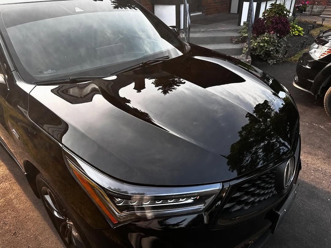 A black Acura RDX hood with a mirror-like reflection after a Keyz Auto Spa ceramic coating
